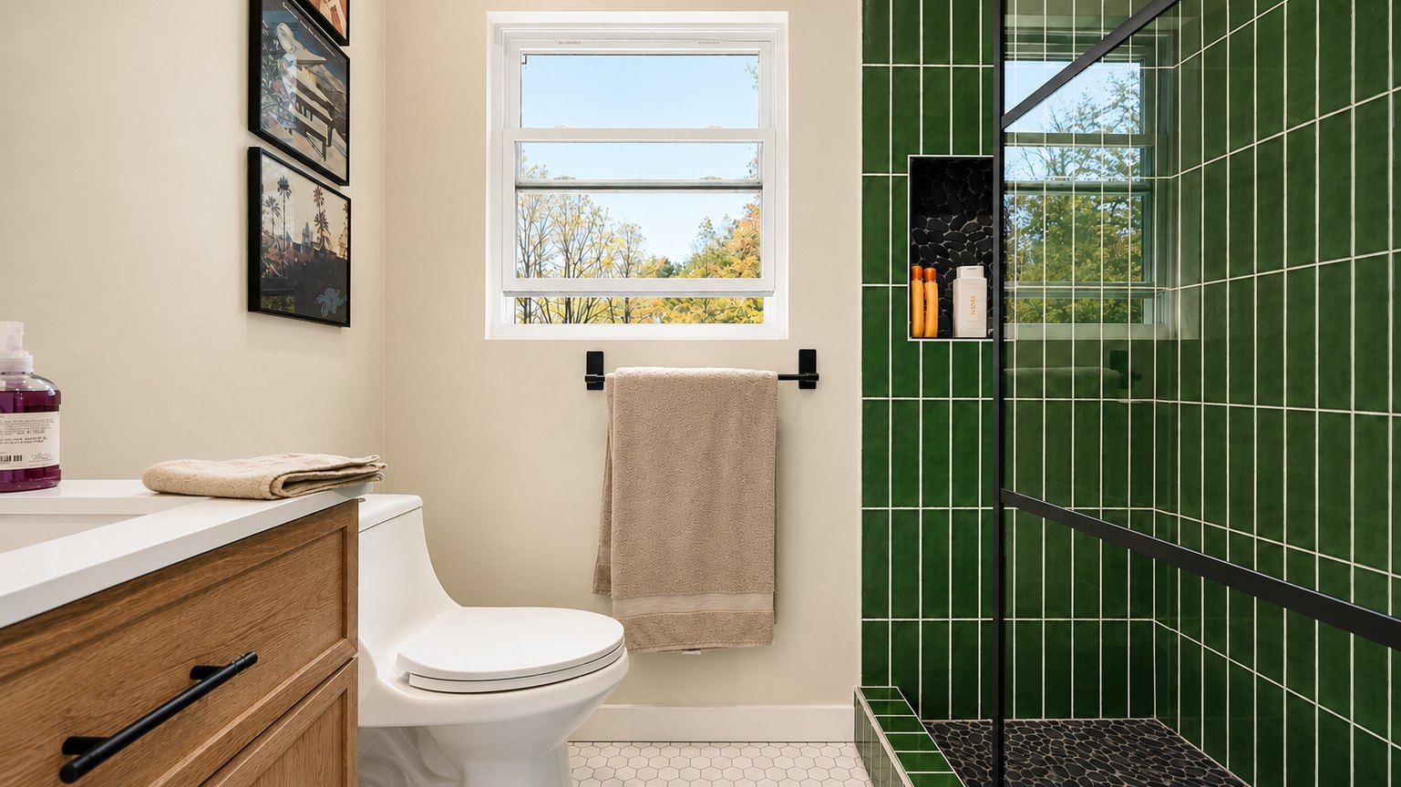 Finished bathroom with green vertical tile shower, oak vanity, and a window with fall tree views