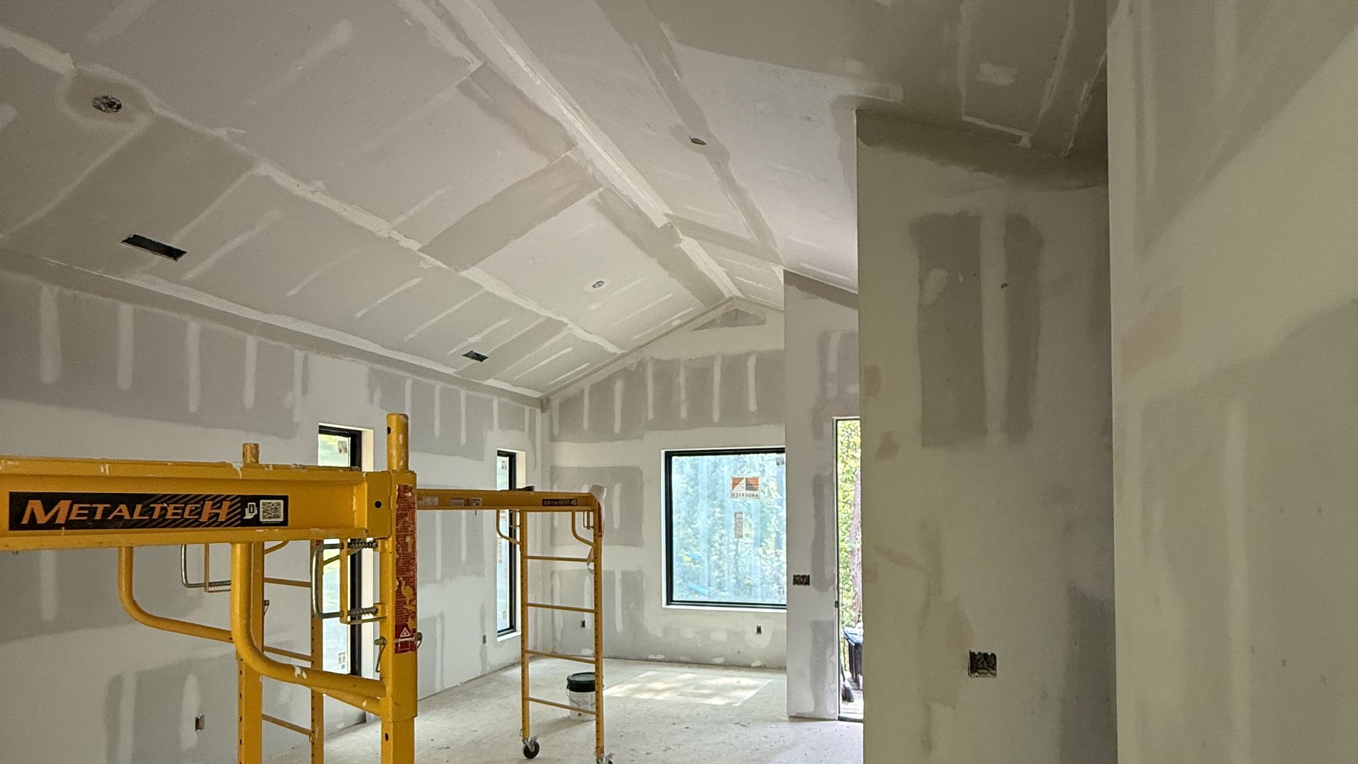 Framed and drywalled room under construction with scaffolding