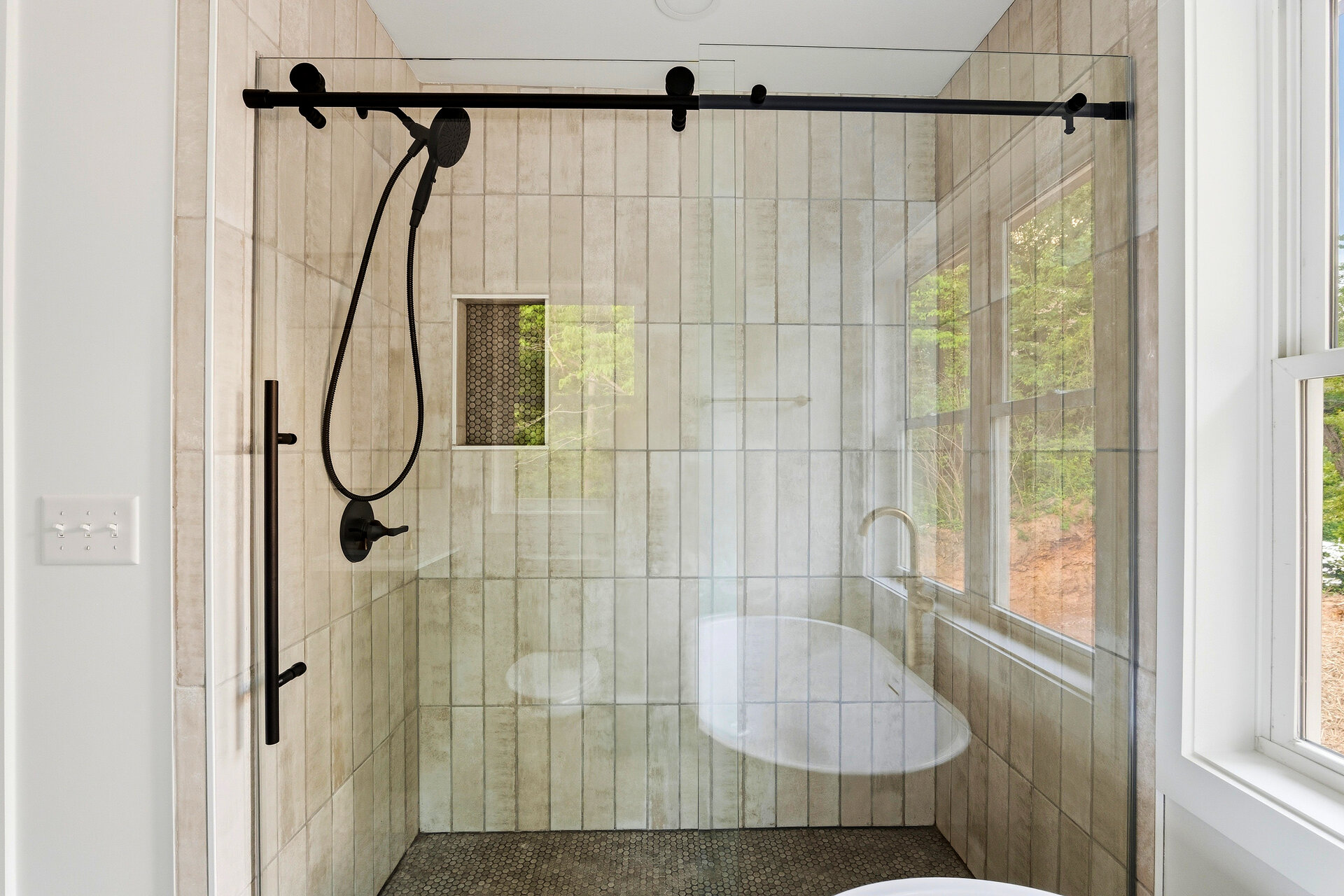 Detail of remodeled tile shower with matte black fixtures by Wooded Mountain Builders
